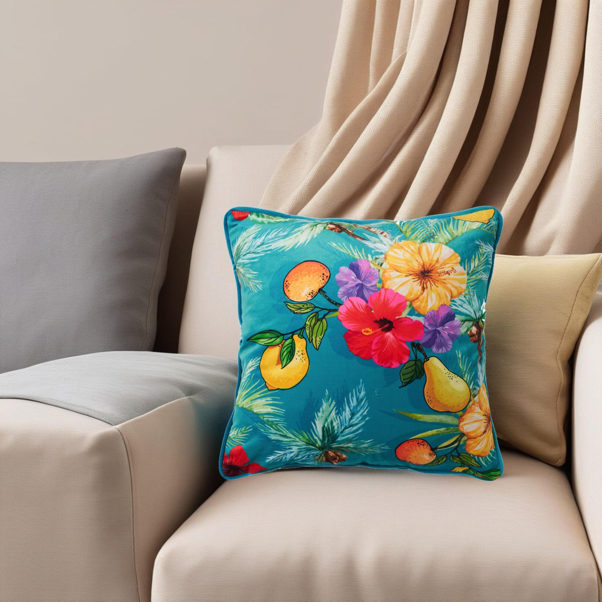 Teal tropical cushion cover styled on a beige sofa beside plain grey and cream cushions