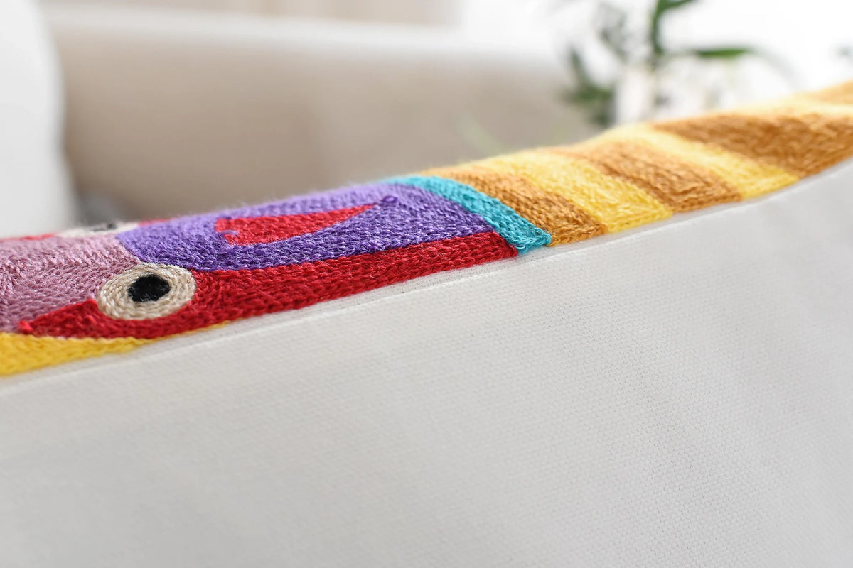 Edge of the embroidered cushion cover showing the stitched colours up to the seam and the plain back