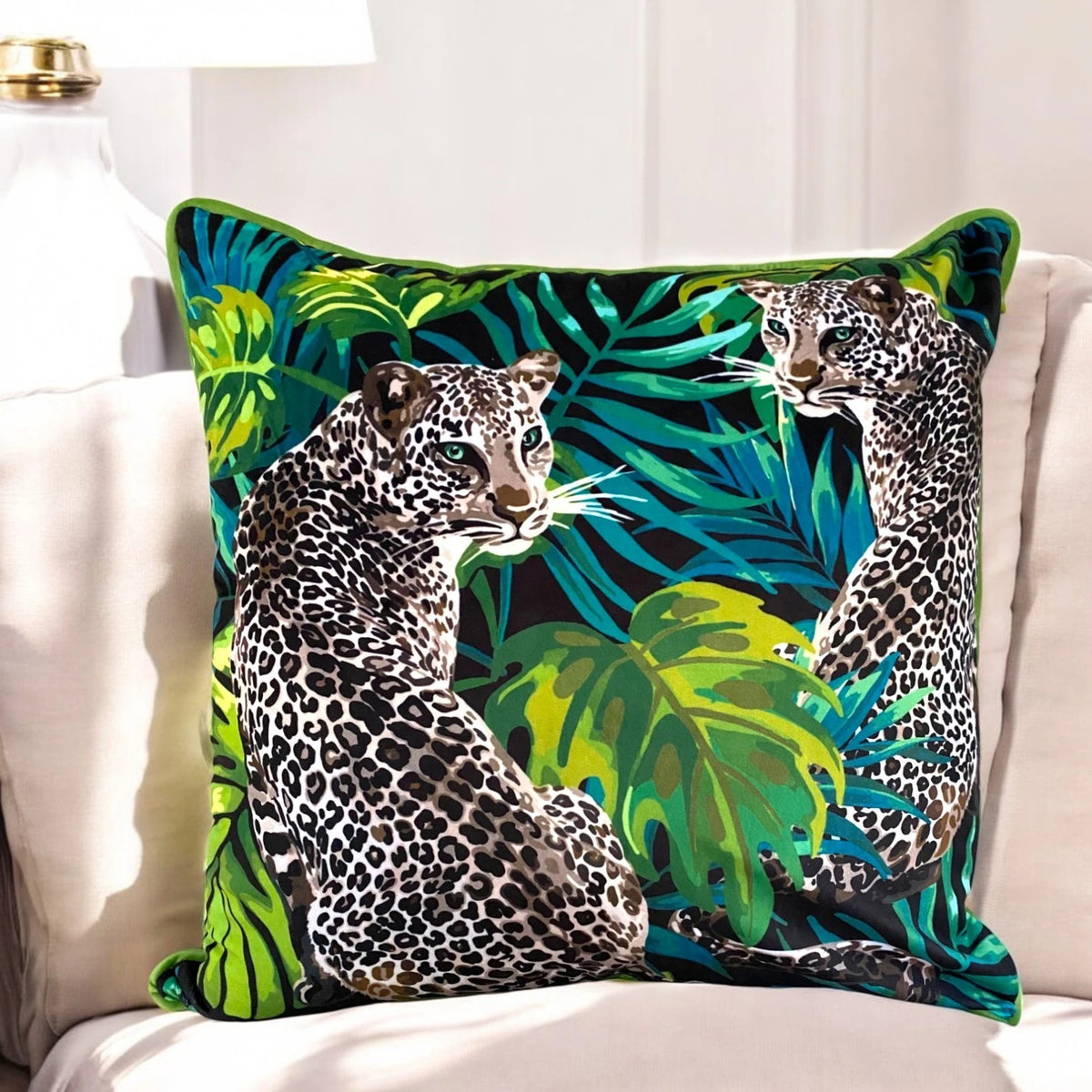 Lemon grass velvet cushion cover 50x50 cm with seated leopards, monstera leaves and lime piping on a cream sofa
