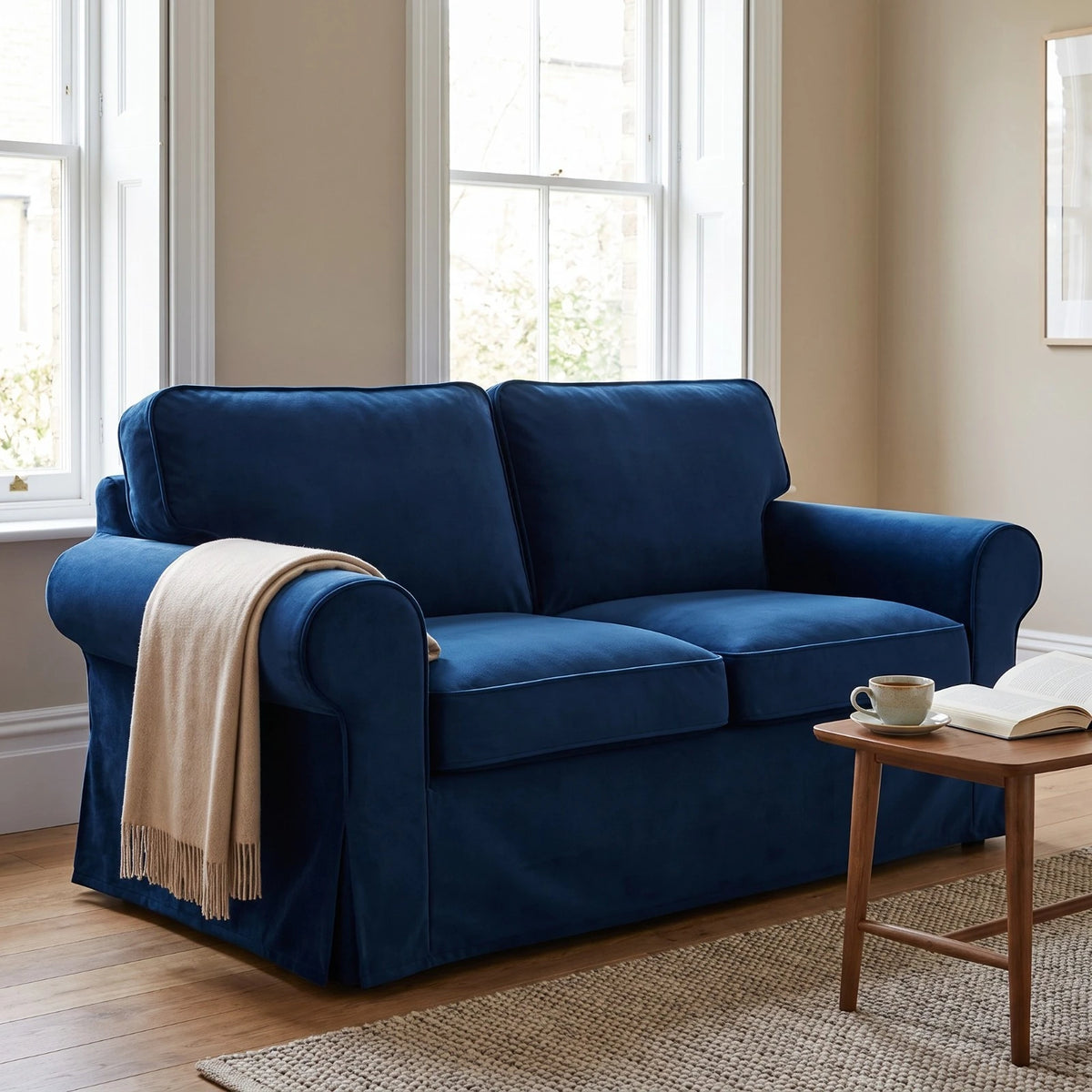 Blue velvet Ektorp sofa cover on a 2 seater in a bright sitting room, styled with a throw and coffee table