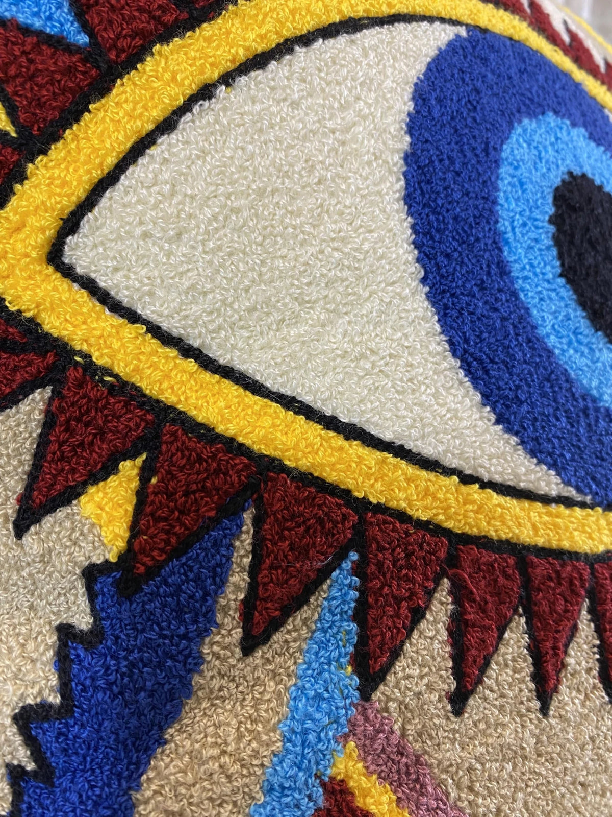 Close-up of the raised cotton loops forming the blue nazar eye on the tufted cushion cover
