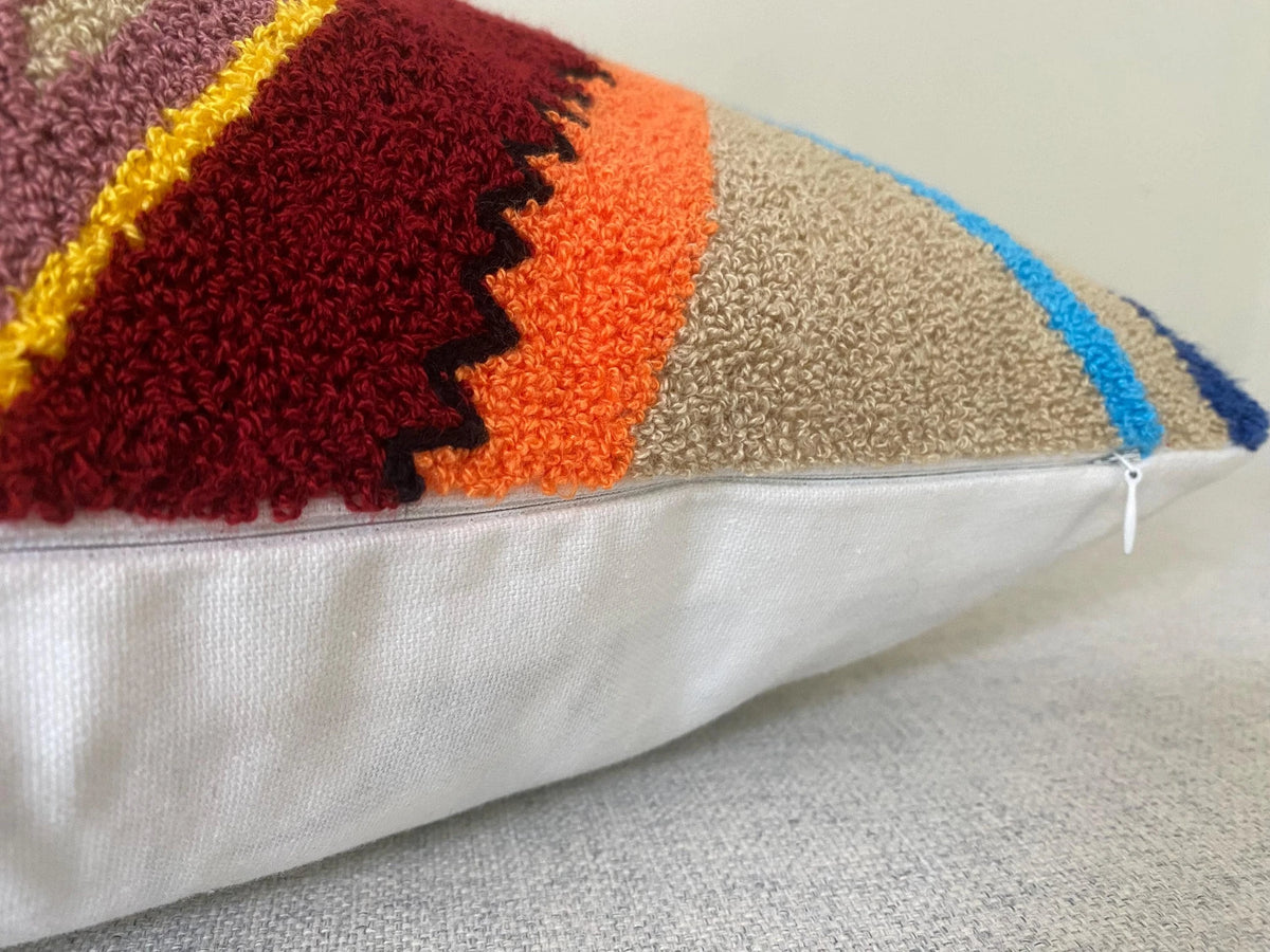 Side view of the evil eye cushion cover showing the tufted front, cream cotton back and zip