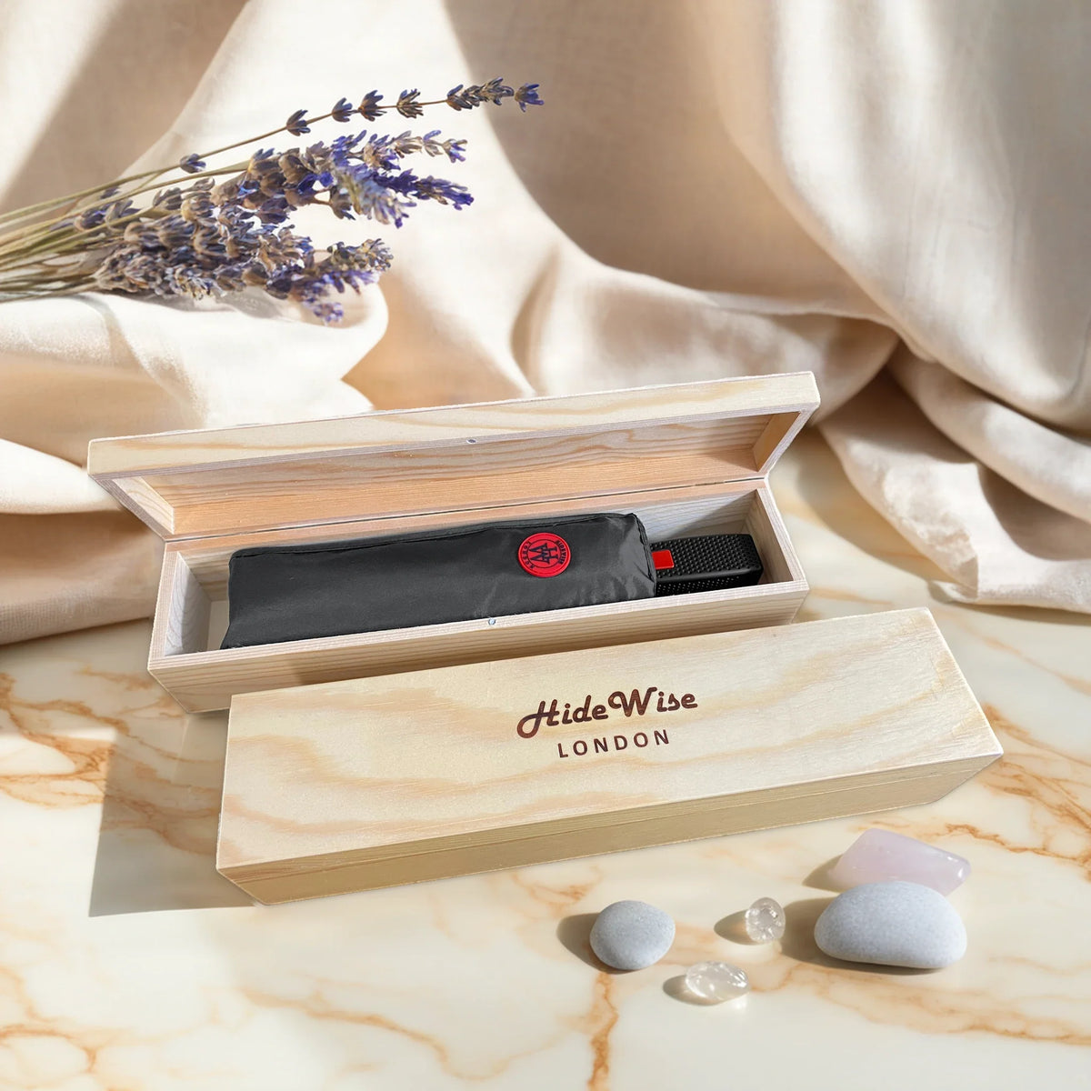 HideWise London graphite grey compact folding umbrella packed in an engraved pine wood gift box, on a marble table