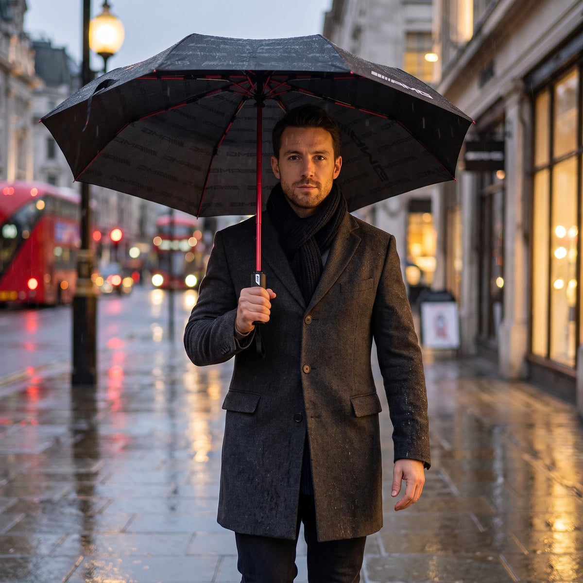 Mercedes-AMG compact folding umbrella in use: man walking in the London rain under the black and red canopy