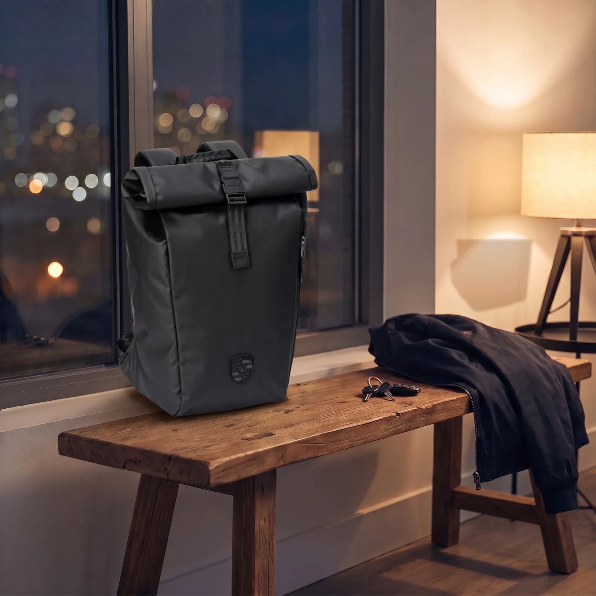 Porsche 911 roll-top laptop backpack on a wooden bench by a window in the evening, beside a jacket and keys
