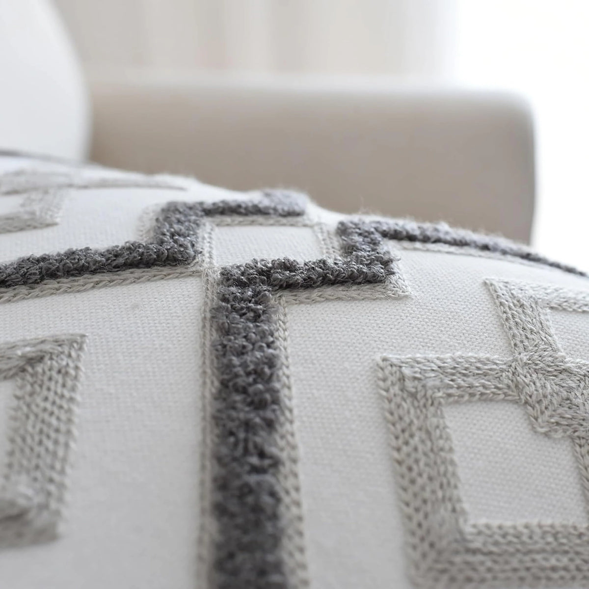 Modern lattice cushion cover detail: a raised, looped dark grey outline around pale grey embroidered diamonds