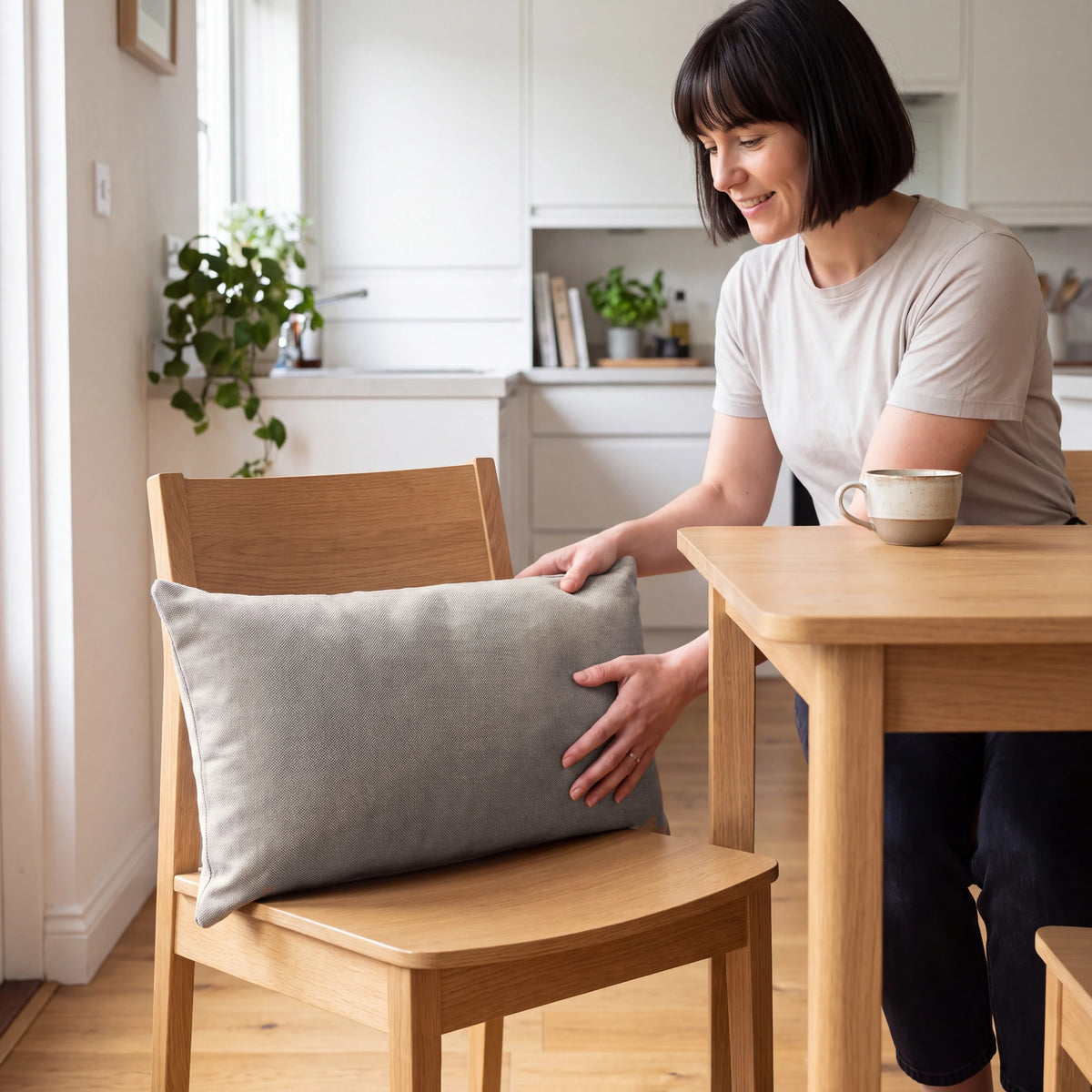 Beige back support cushion being placed on an oak dining chair at the kitchen table