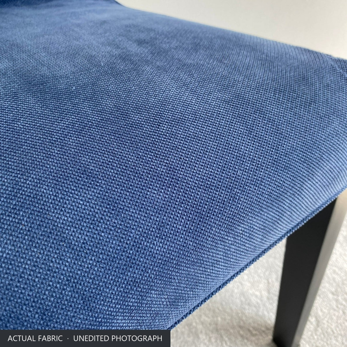 Close-up of the denim blue stretch-woven polycotton on the seat of the Bergmund chair cover
