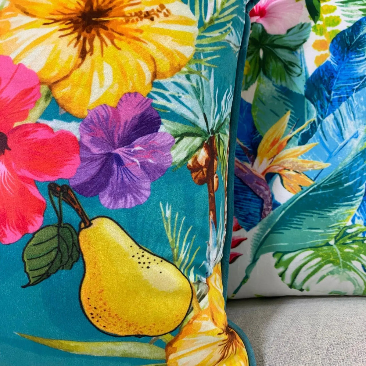Close-up of the plush velvet tropical cushion cover showing the printed pear, hibiscus and piping