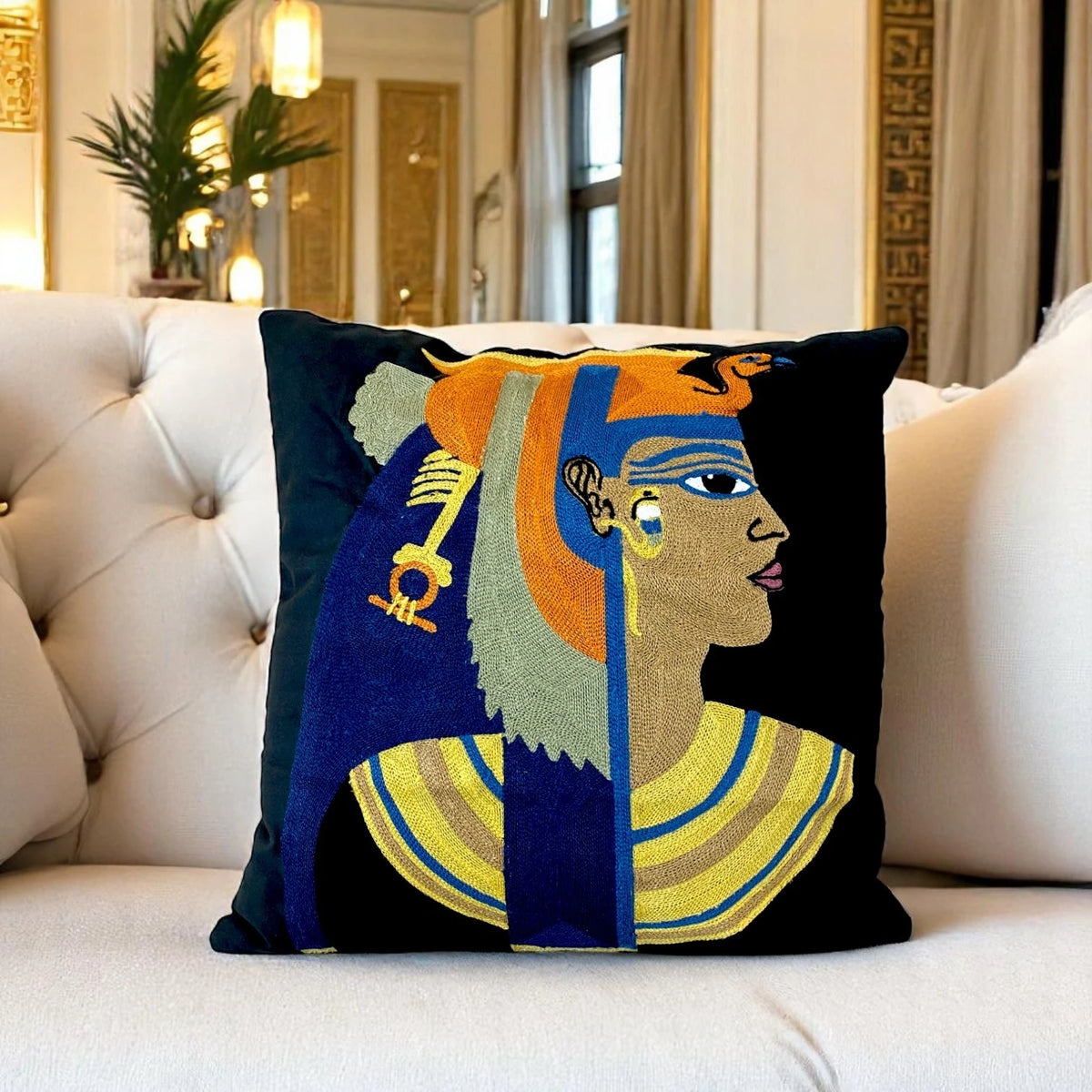 Black Cleopatra cushion cover on a buttoned cream sofa in a gold-toned Egyptian-style room