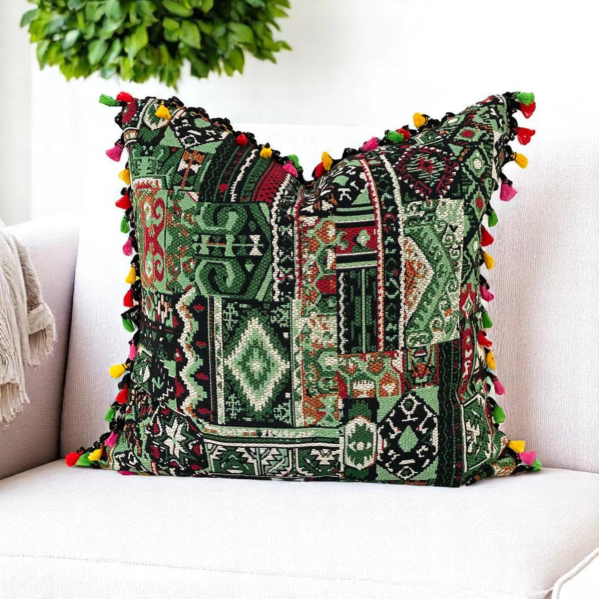 Green patchwork cushion cover with pink, red and yellow tassels styling a white armchair