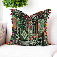 Green patchwork cushion cover with pink, red and yellow tassels styling a white armchair