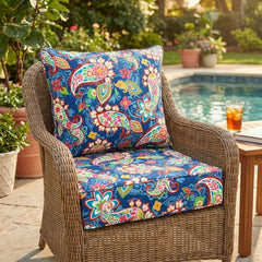 Outdoor cushion set in navy paisley floral on a rattan armchair beside a swimming pool