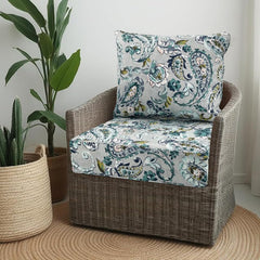 Grey blue paisley outdoor seat and back cushions on a wicker tub chair beside house plants