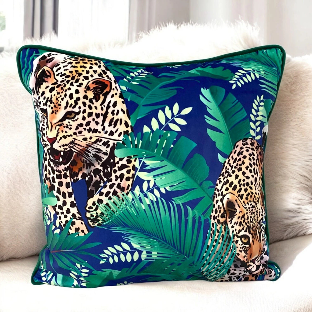 Blue green velvet cushion cover 50x50 cm with leopard and tropical leaf print and green piping on a cream sofa