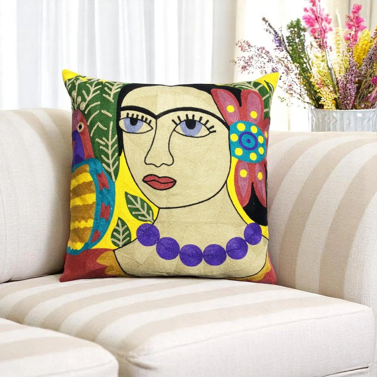 Colourful folk-art embroidered cushion cover with a portrait design on a striped cream sofa
