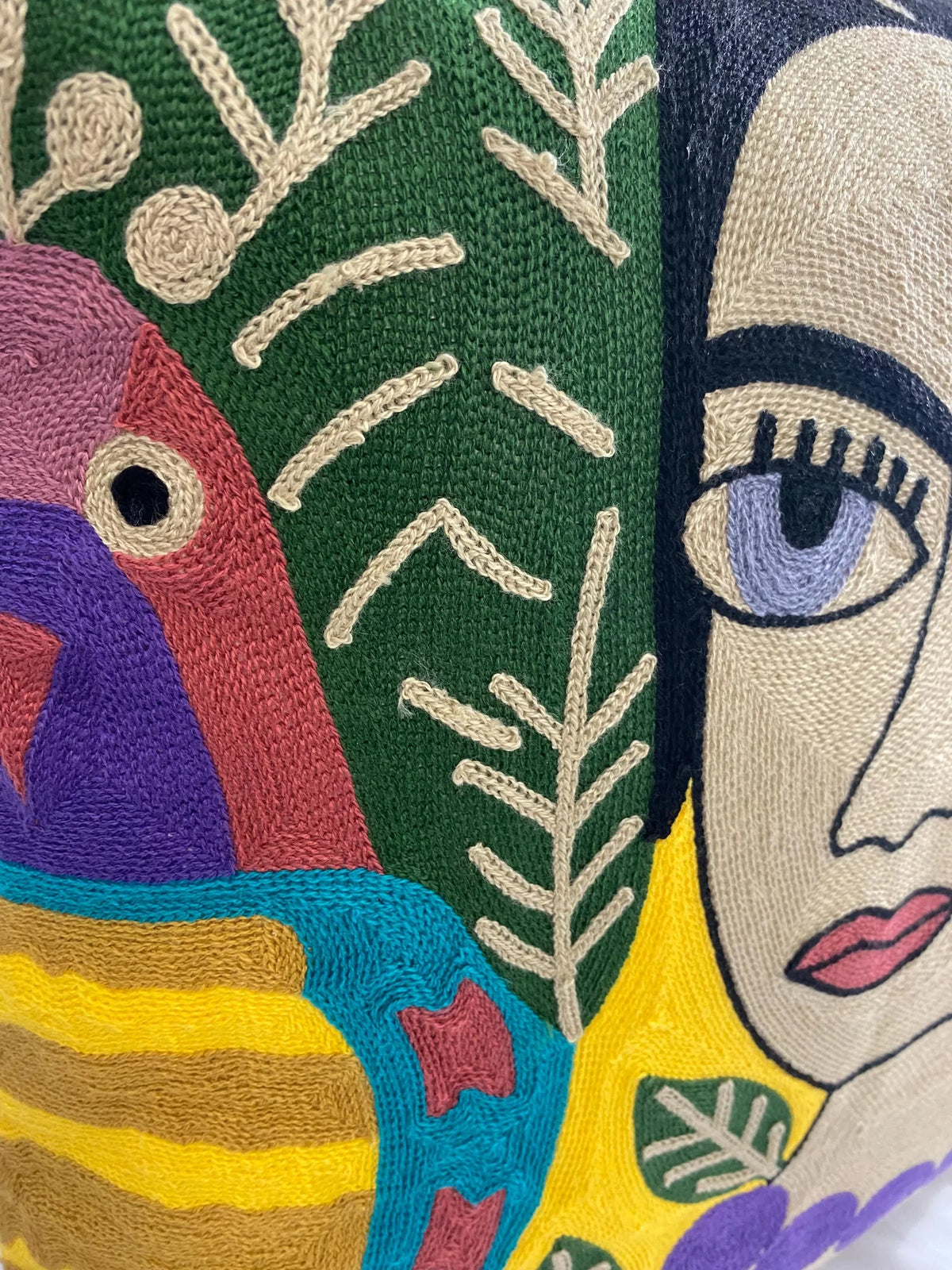 Close-up of the chain-stitch embroidery on the cushion cover: parrot, green leaves and portrait eye