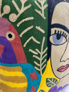 Close-up of the chain-stitch embroidery on the cushion cover: parrot, green leaves and portrait eye