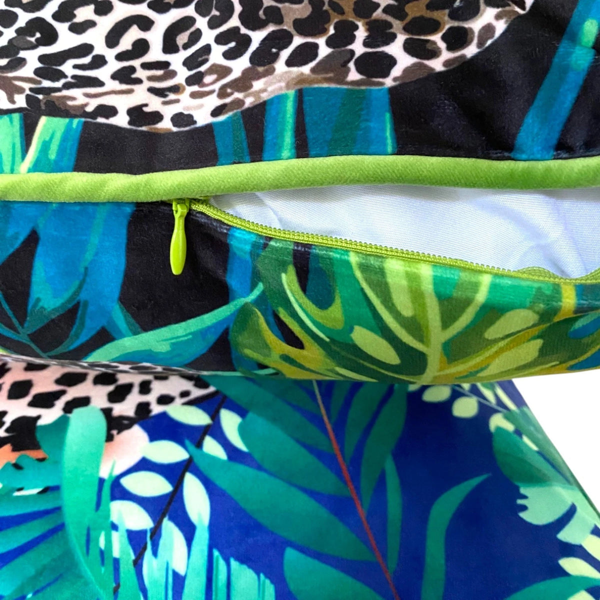 Lime-green zip and piping along the seam of the black leopard print velvet cushion cover, shown open