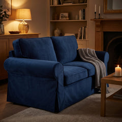 Ektorp 2 seat sofa dressed in a blue velvet replacement cover by lamplight, with a knitted throw