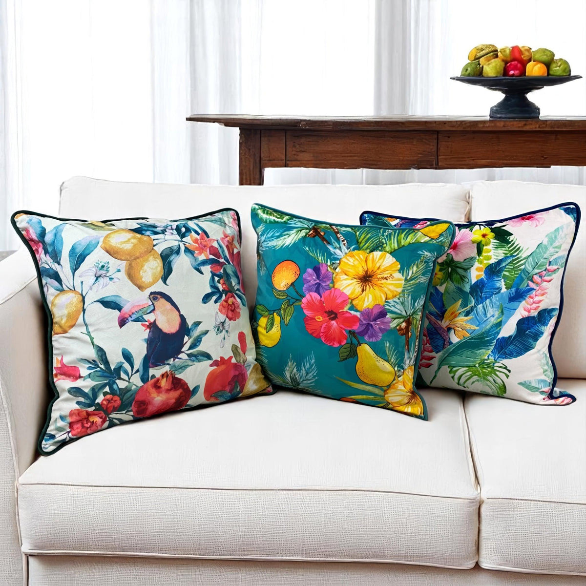 Tropical velvet cushion covers set of 3 on a white sofa: toucan, teal fruit and ivory floral prints