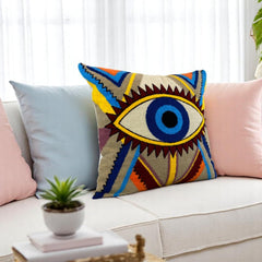 Tufted evil eye cushion cover on a cream sofa between pale blue and blush pink cushions