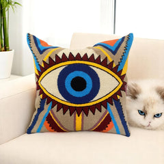 Boho evil eye cushion cover on a cream sofa with a fluffy cat beside it