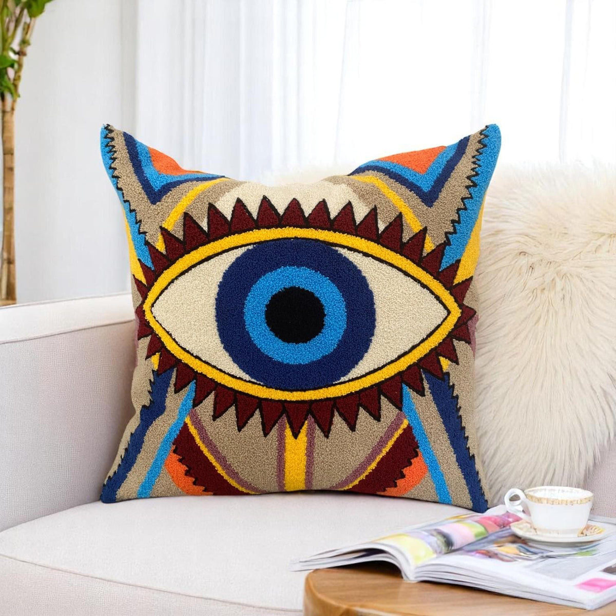 Turkish nazar cushion cover on a white sofa next to a sheepskin, a magazine and a teacup