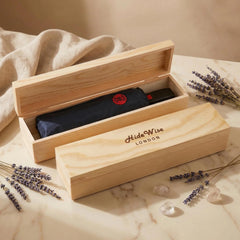 Pine wooden gift box open with the black compact folding umbrella packed inside, ready to give