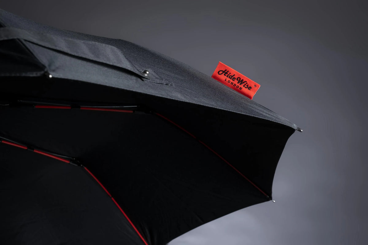 Close-up of the black UV umbrella canopy edge with red ribs and the red HideWise London label