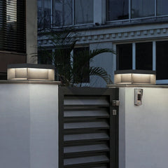 Pair of square gate post lights glowing on rendered pillars either side of a garden gate