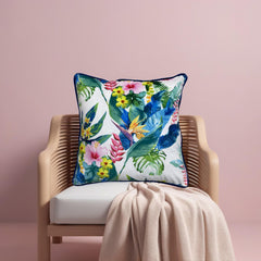 Ivory floral cushion cover on a rattan chair against a blush pink wall with a knitted throw