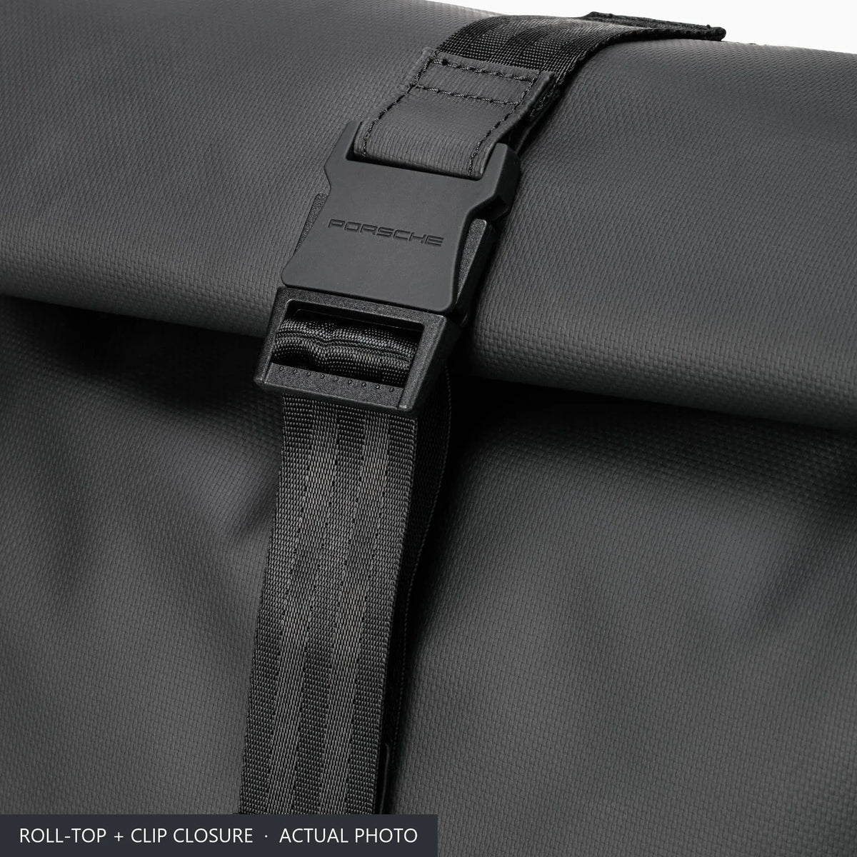 Clip buckle and webbing strap closing the roll top of the black Porsche 911 backpack