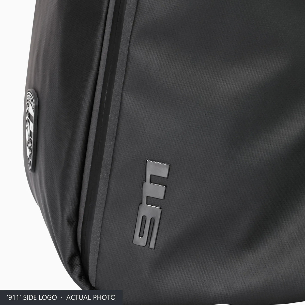 Raised '911' logo on the side panel of the black Porsche roll-top backpack, close-up