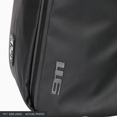 Raised '911' logo on the side panel of the black Porsche roll-top backpack, close-up