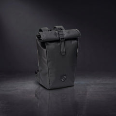 Black Porsche 911 roll-top backpack standing on a glossy dark studio floor, front view with the 3D crest