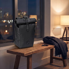 Porsche 911 roll-top laptop backpack on a wooden bench by a window in the evening, beside a jacket and keys