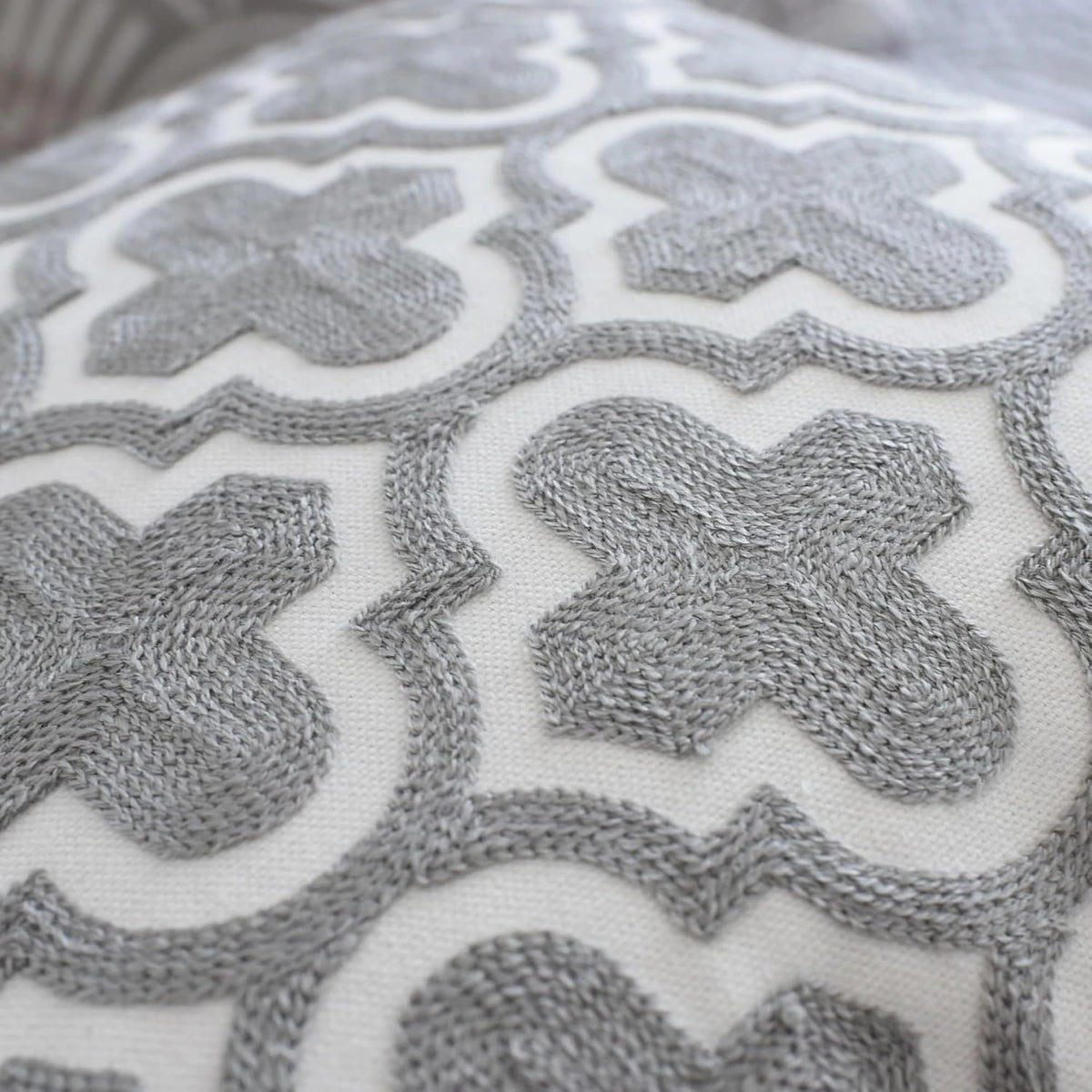 Moroccan trellis embroidery in grey on white cotton, a detail of one 50x50 cm cushion cover in the set