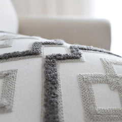 Modern lattice cushion cover detail: a raised, looped dark grey outline around pale grey embroidered diamonds
