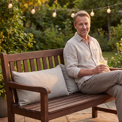 Beige outdoor lumbar cushions on a wooden garden bench on a summer evening