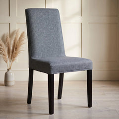 Grey Bergmund chair cover with a melange weave on a dining chair in a panelled room